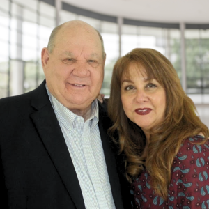 A smiling pastor, standing in front of a church backdrop with warm lighting.